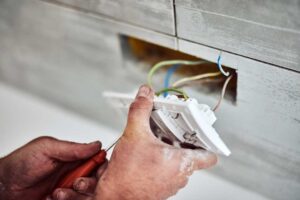 A person inspecting a circuit breaker panel with a flashlight in a residential basement.