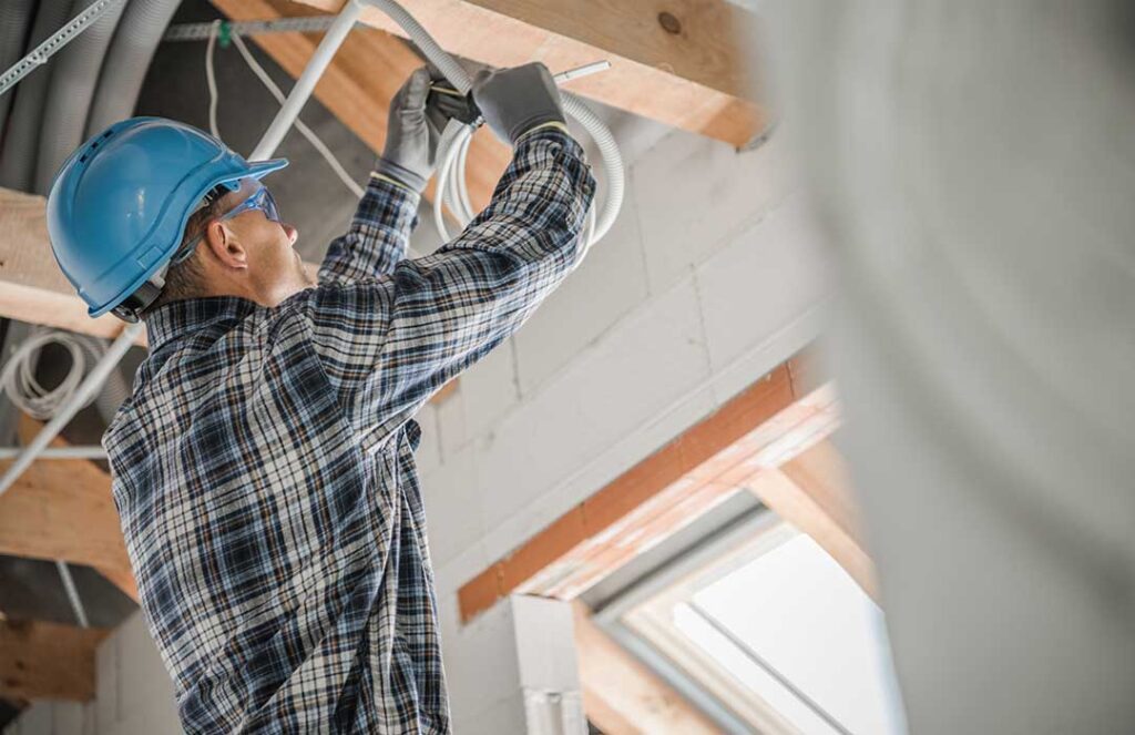 A person safely replacing a ceiling light fixture with the power turned off in a residential room.